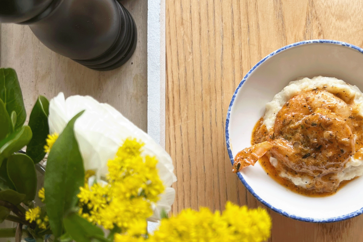 a plate of shrimp and grits sitting on top of a wooden table