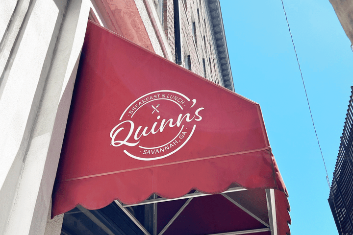 Red awning with text 'Quinn's Breakfast & Lunch, Savannah, GA' against blue sky.