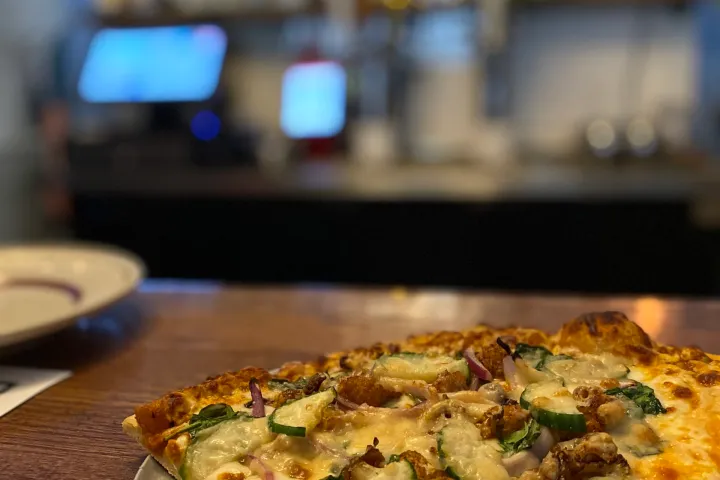 a slice of pizza sitting on top of a wooden table