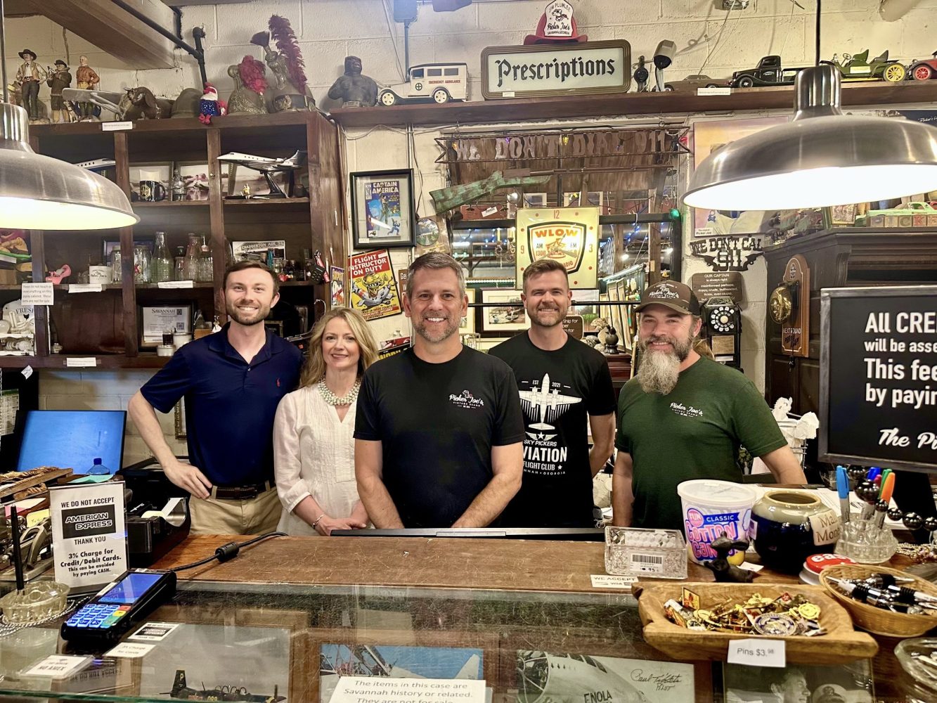 Picker Joe's team smiling behind a store counter with vintage decor and signs.