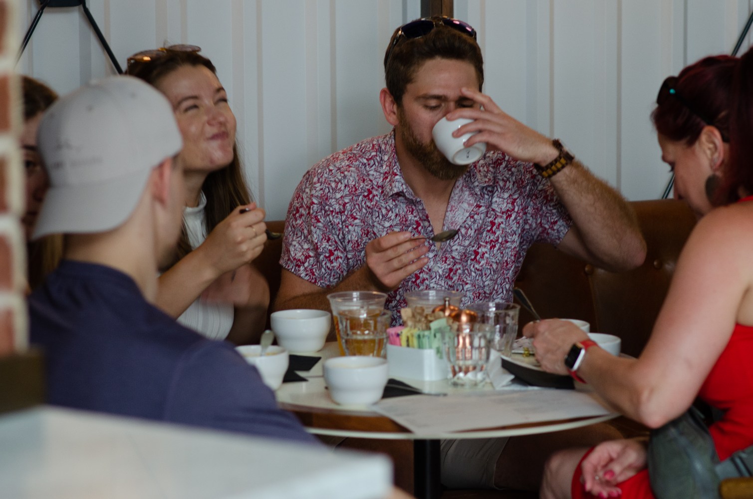 Group of people eating and drinking at a round table in a restaurant.