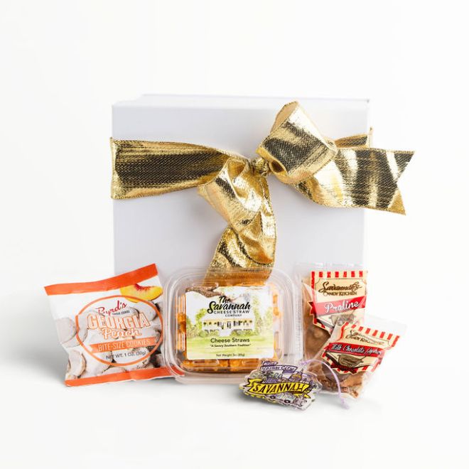 Gift box with gold bow and assorted snacks displayed in front.