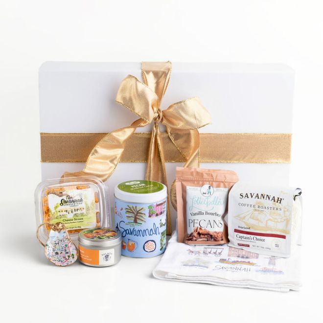 Gift box with gold ribbon, nuts, coffee, and snacks arranged outside it.