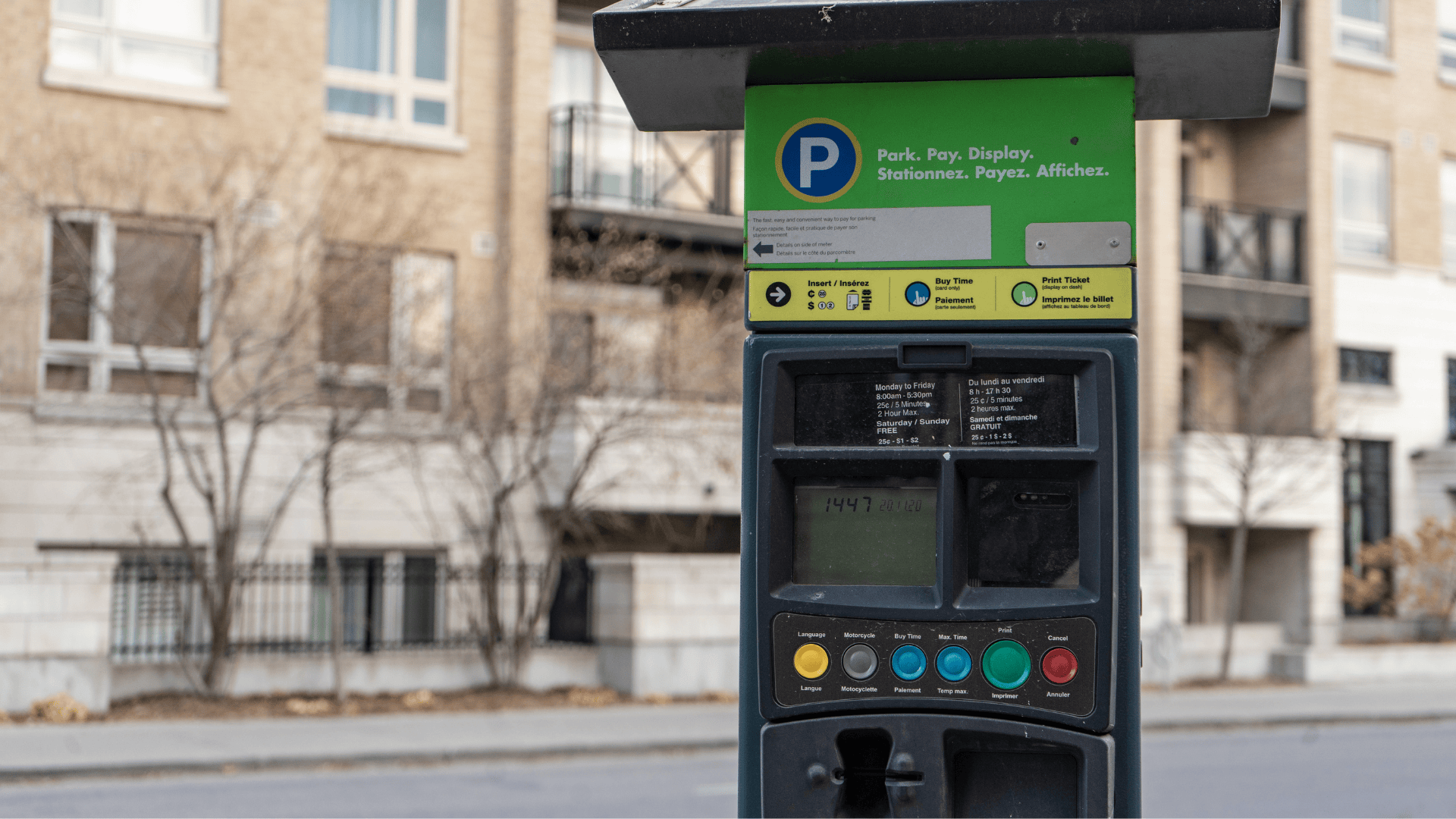 Street parking meter with buttons in an urban area.